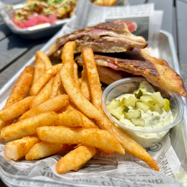Crooked Tale Gastropub's grilled sandwich with melted cheese, fries, and a side of tartar sauce.
